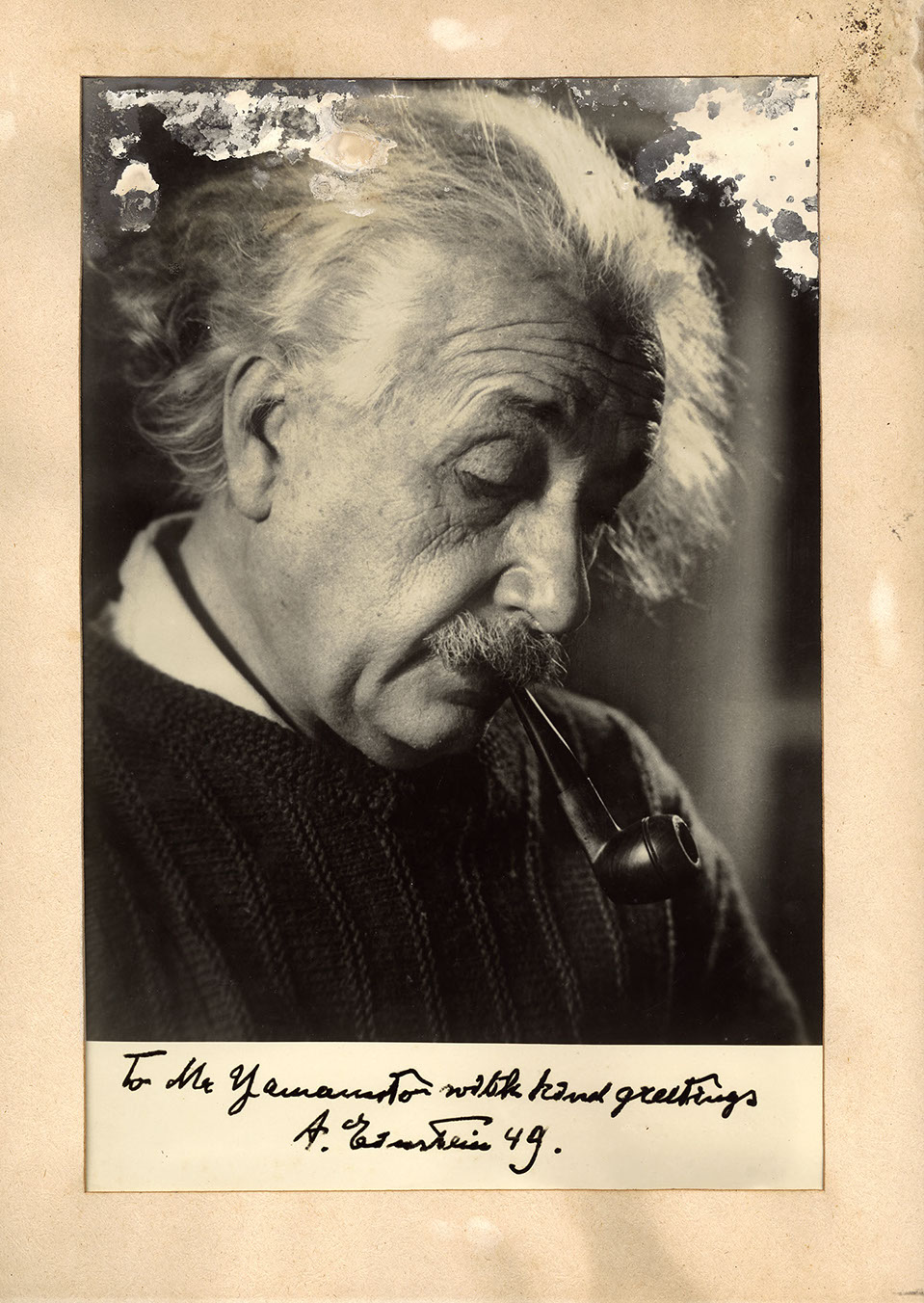This is a photograph portrait of Albert Einstein smoking a pipe and looking away from the camera. Below the photo, it is signed for Yamamoto. 