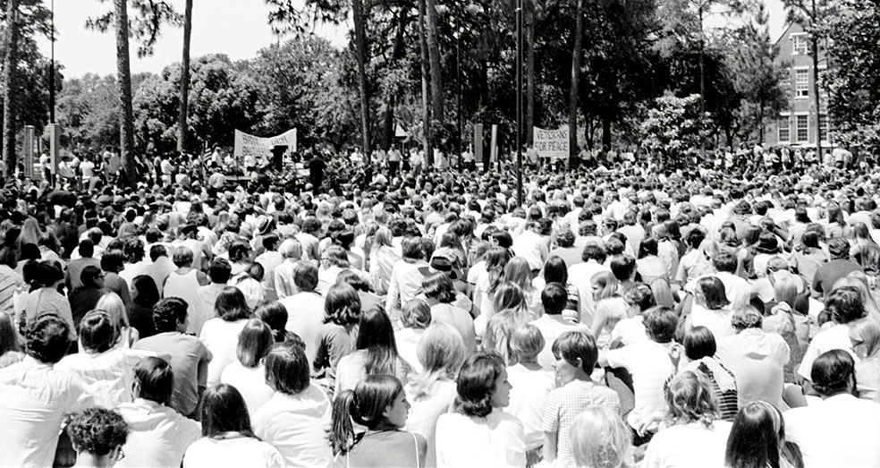 A large crowd wearing white sitting on the Plaza of the America during a Vietnam War protest in 1972
