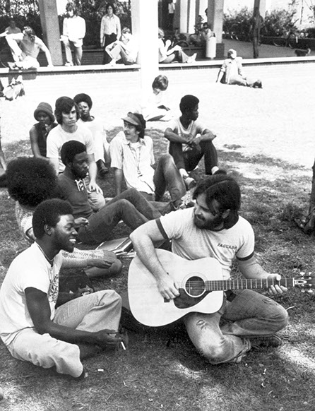 1970s Black and white photograph showing University of Florida student playing guitar while other students listen on the Plaza of the Americas.